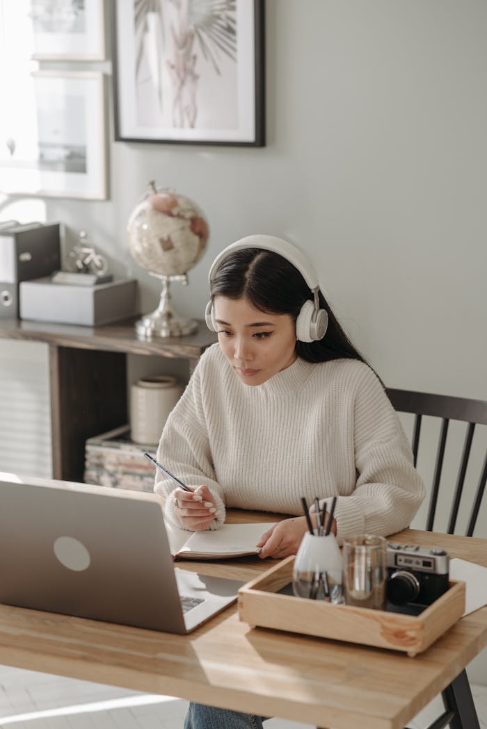 journey Woman wearing headphones focused on studying with laptop at home.